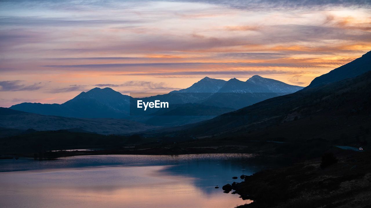 Scenic view of lake and mountains against sky during sunset