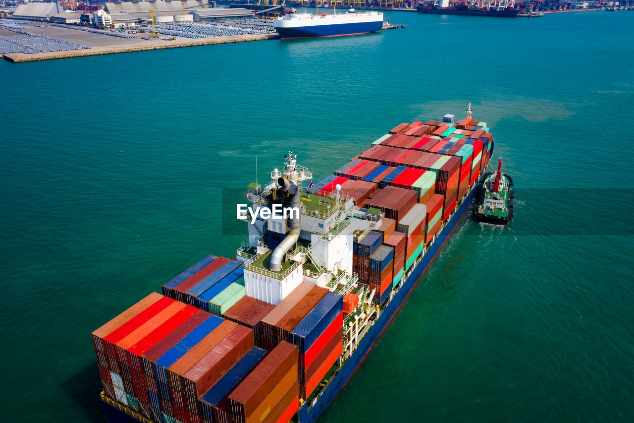 Container ship sailing in green sea and tugboat drag shipping to seaport at leam chabang chonburi 