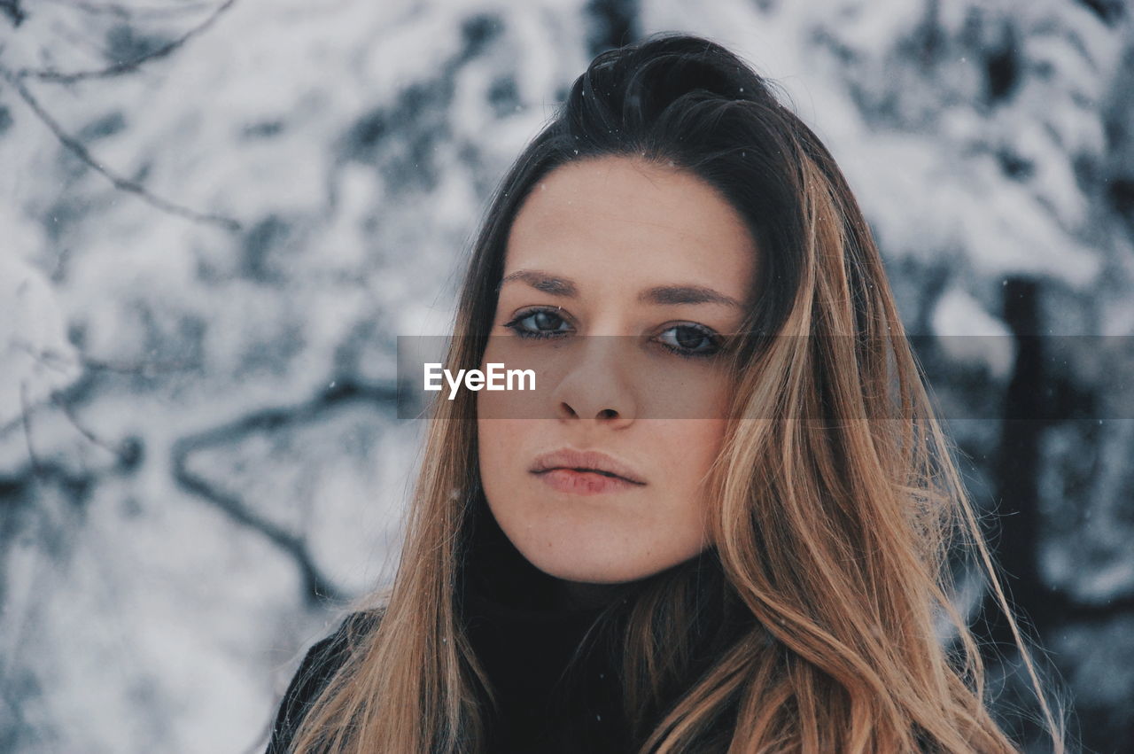 Portrait of woman standing against trees during winter