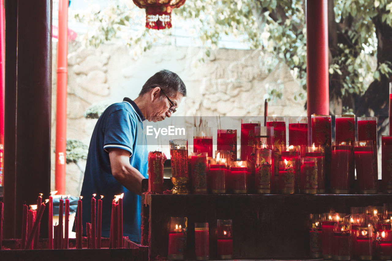 Man standing by lit candles in temple