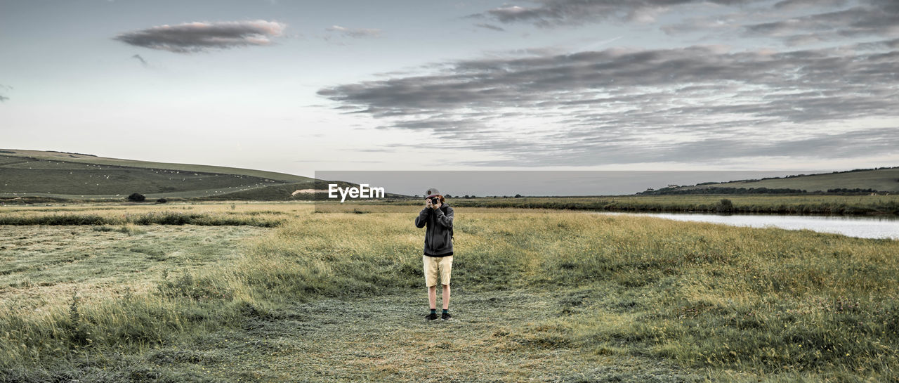 Full length of man photographing on grassy field