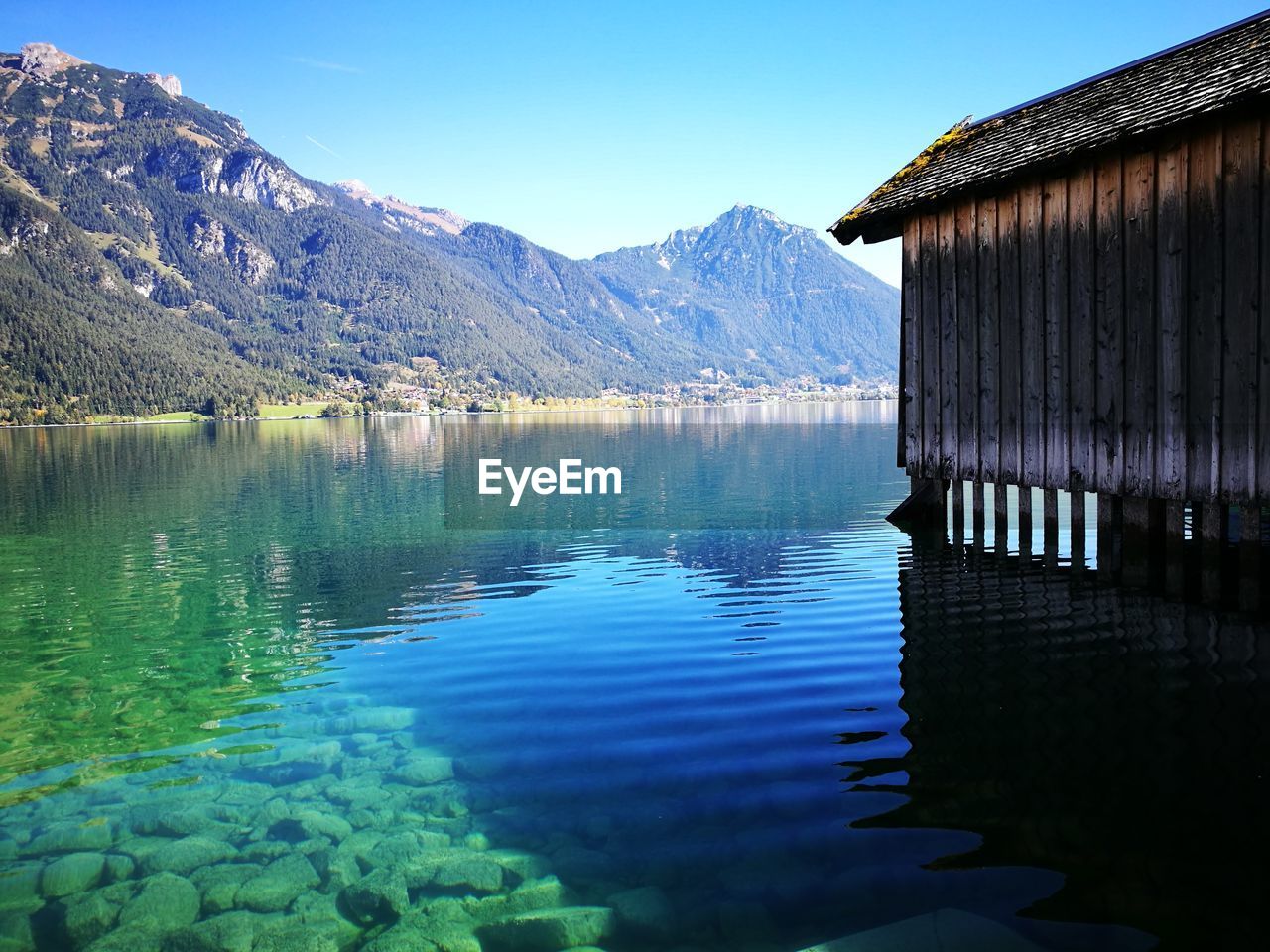 Scenic view of lake and mountains against clear blue sky