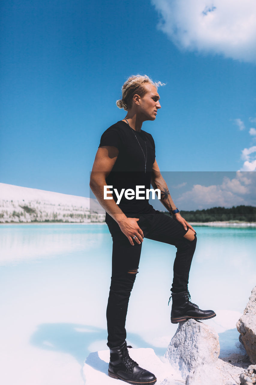 MAN LOOKING AT LAKE AGAINST SKY