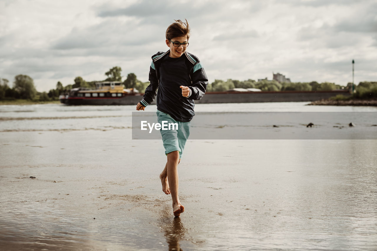 Full length of boy on beach against sky