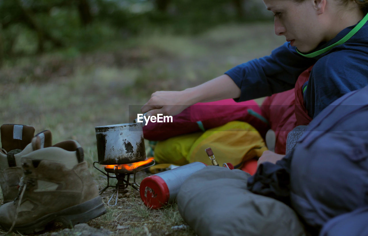 Woman preparing food on camping stove during sunset