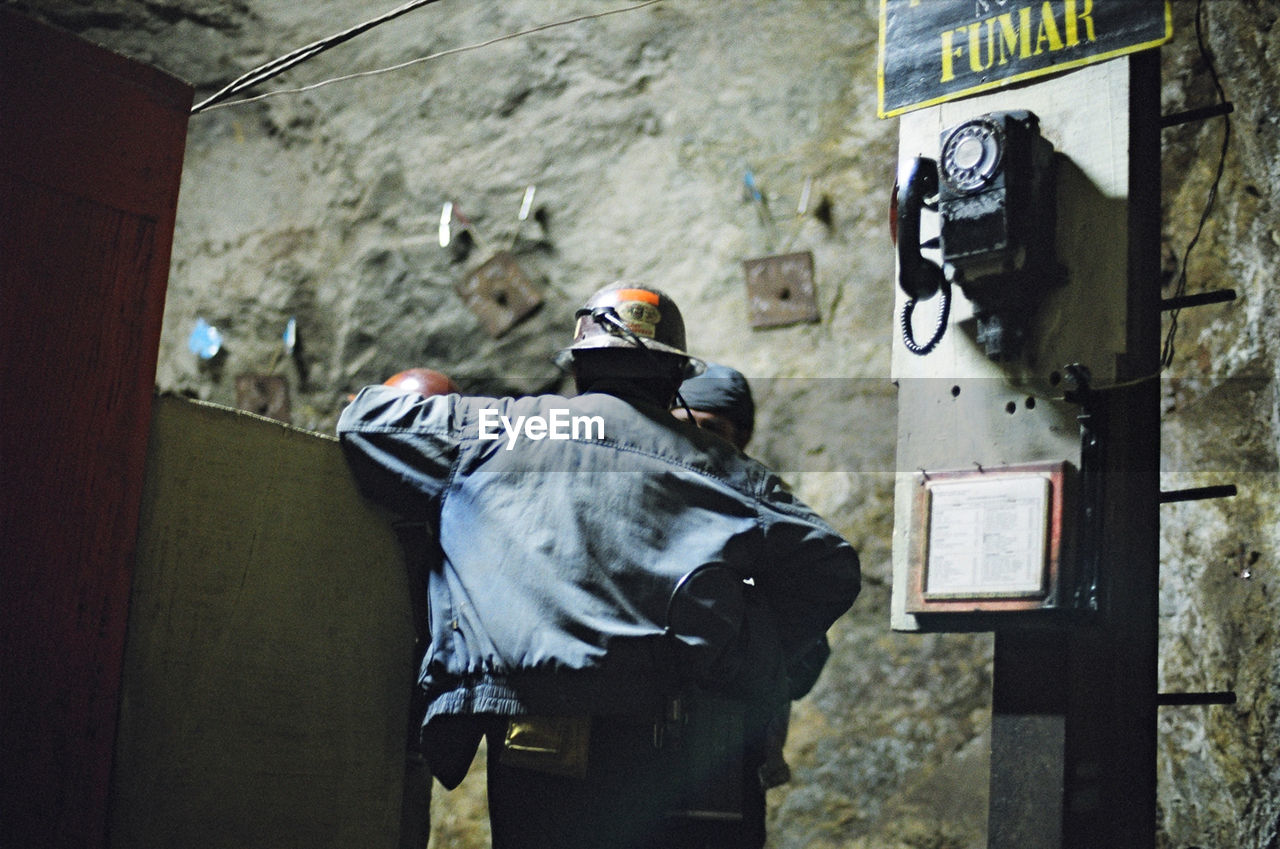 REAR VIEW OF MAN STANDING ON WALL