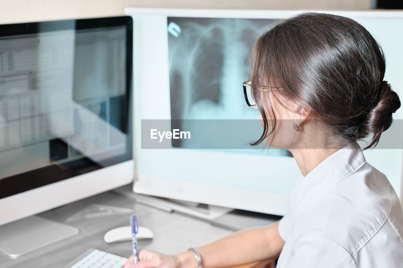 Young asian woman radiologist doctor analysis pulmonary x-ray and make a medical description