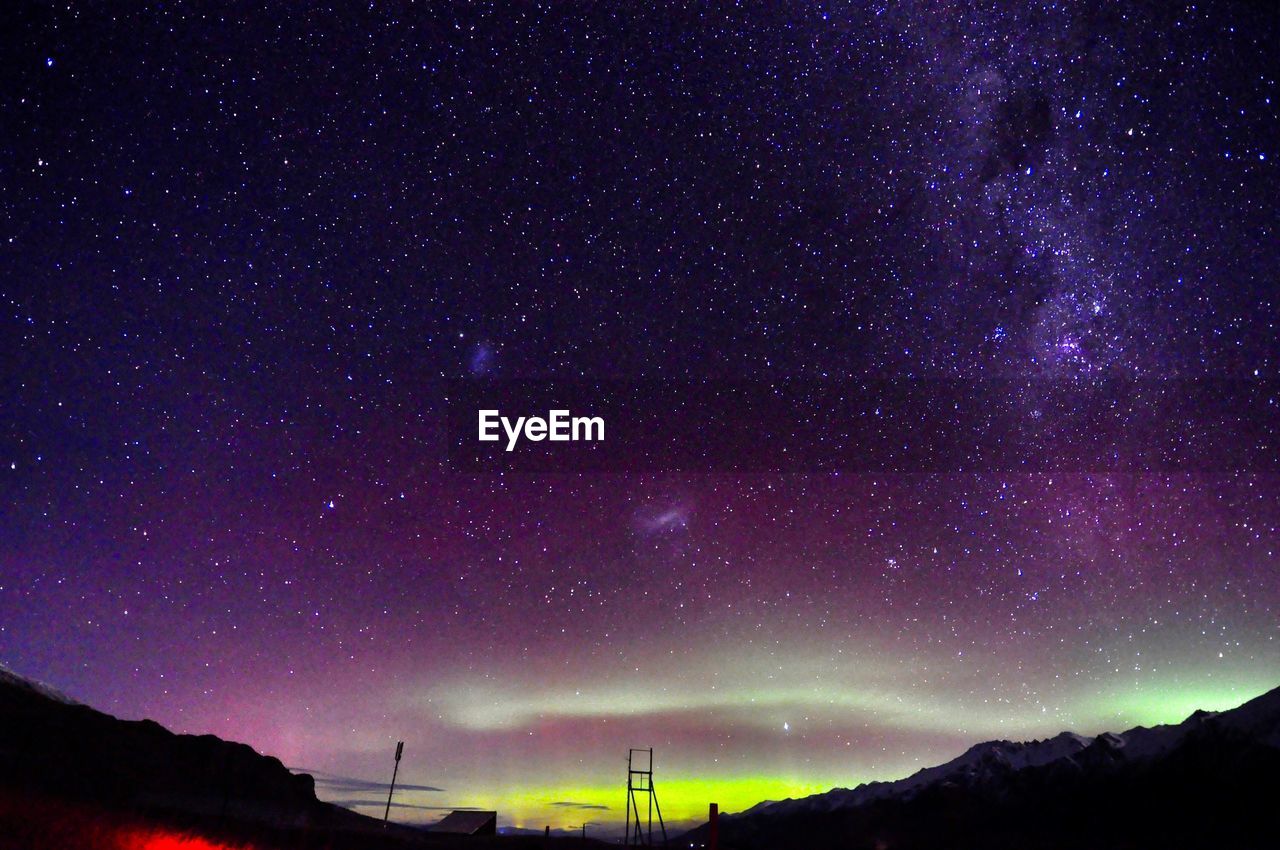 LOW ANGLE VIEW OF STARS ON FIELD AGAINST STAR TRAILS