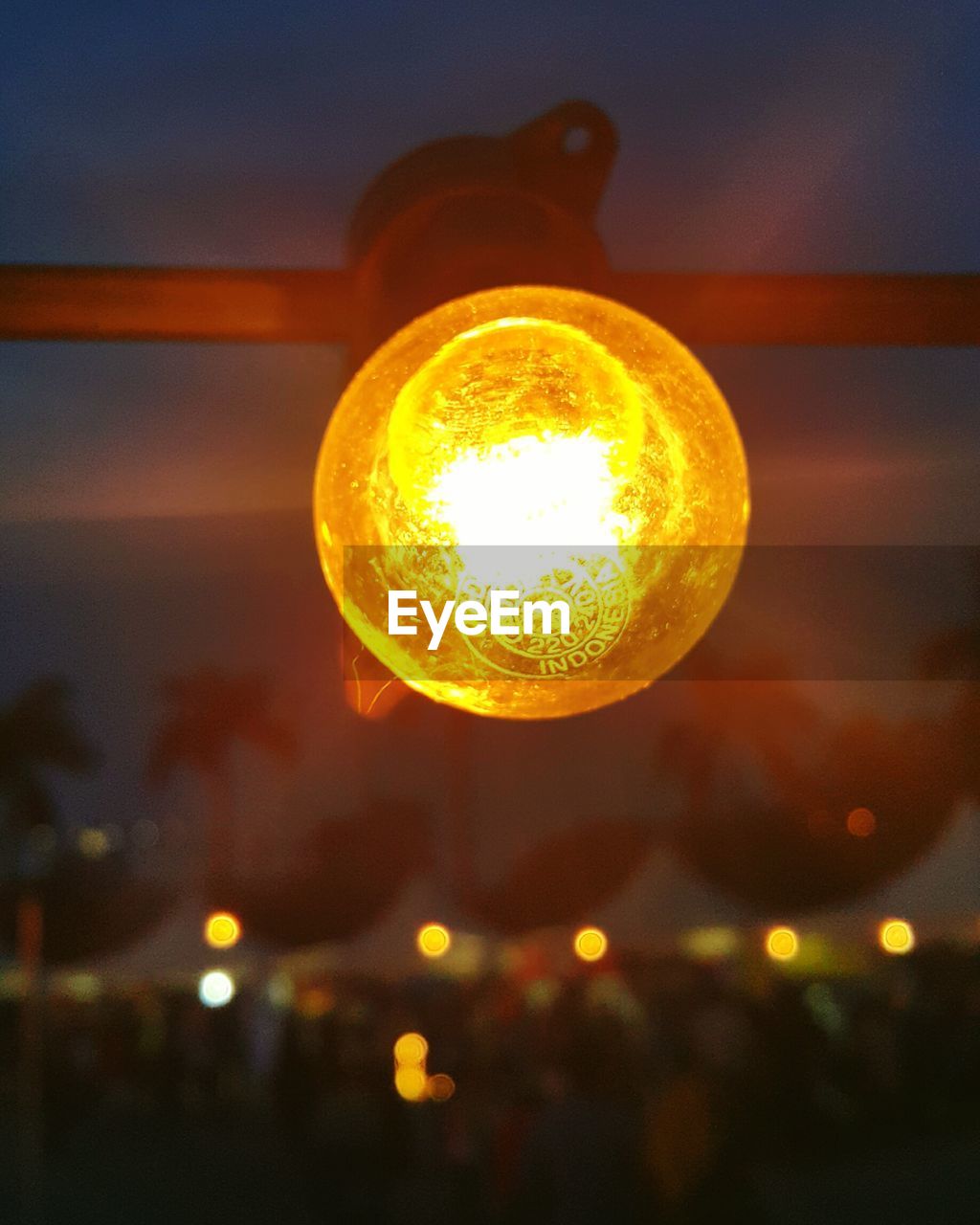 Close-up of illuminated light bulb against sky at night