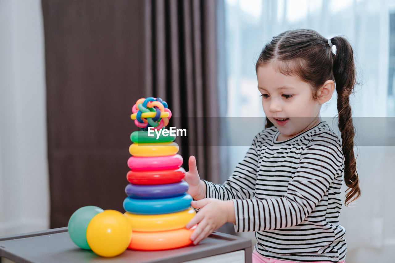 Girl playing with multi colored toys at home