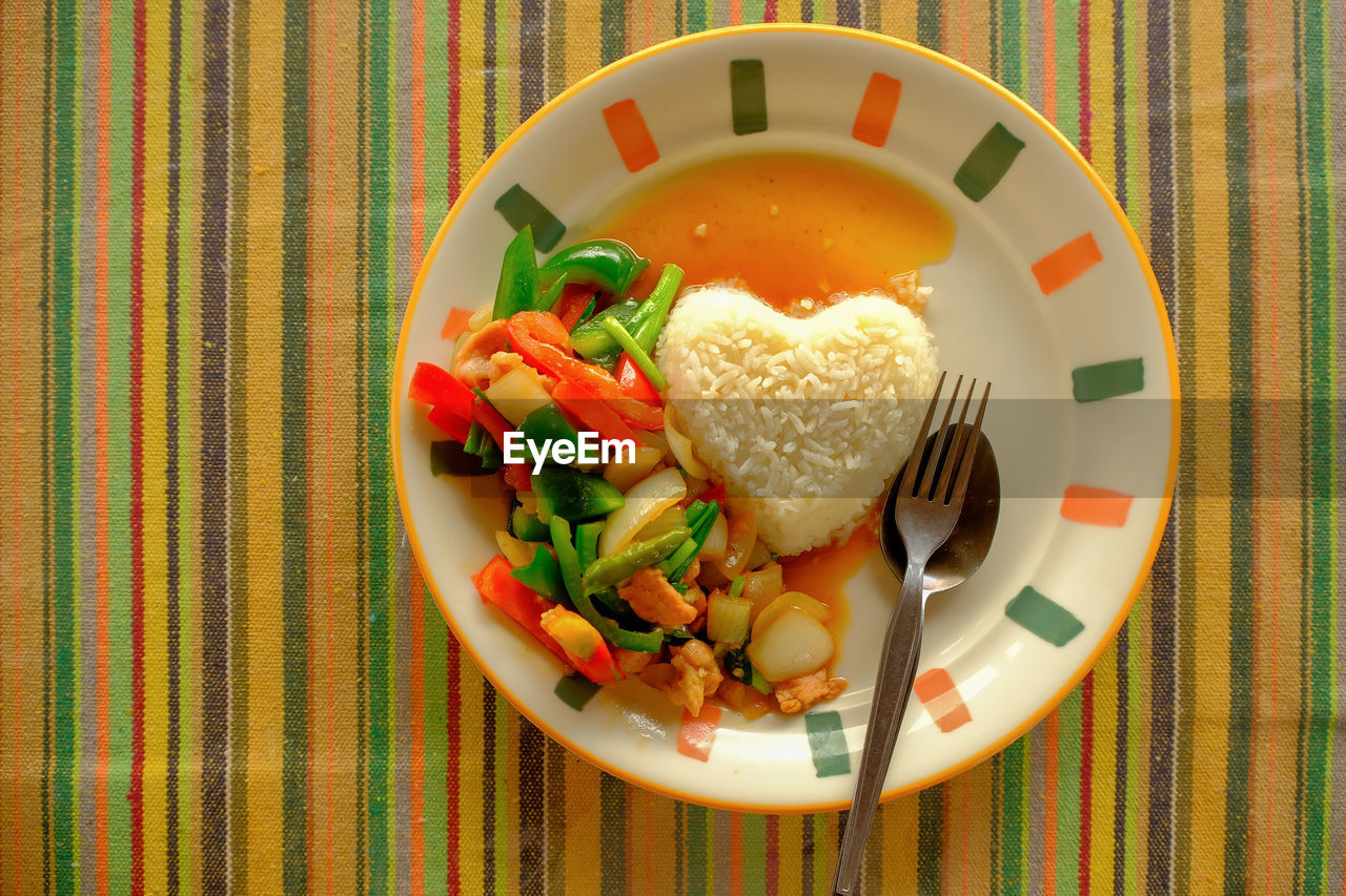 Stir fired vegetable with rice, heart shape serving on rainbow sheet table, lovely meal serving 