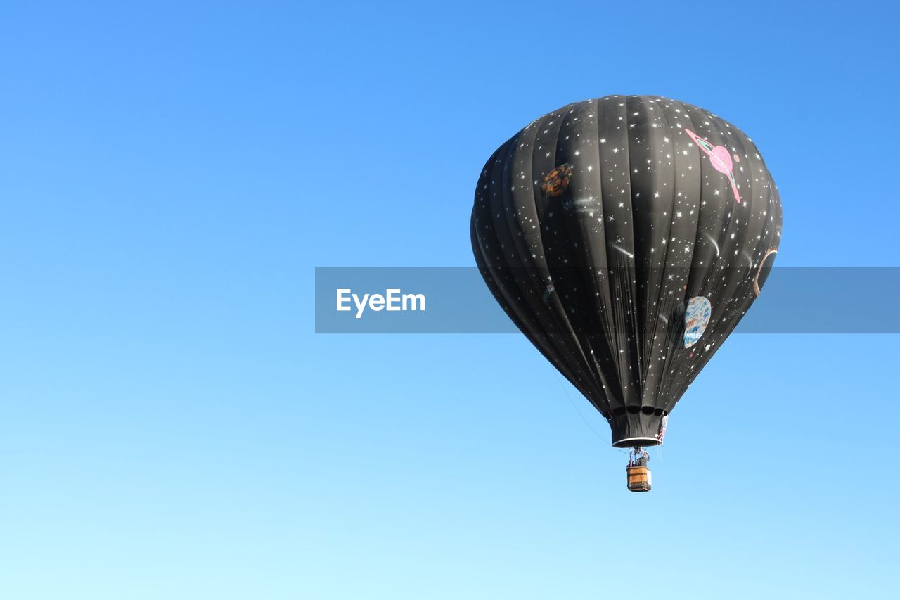 Low angle view of hot air balloon flying in clear blue sky