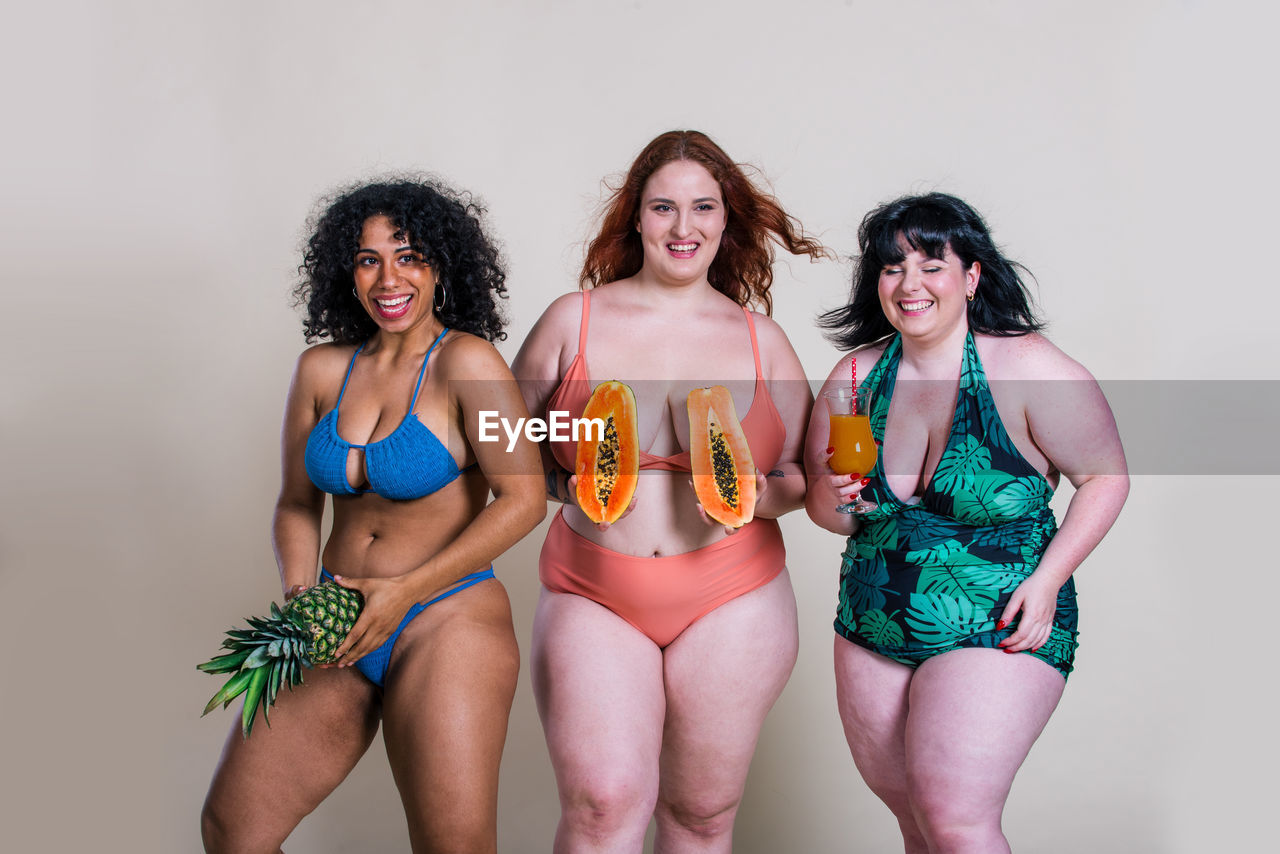 Portrait of smiling women holding fruits standing at home