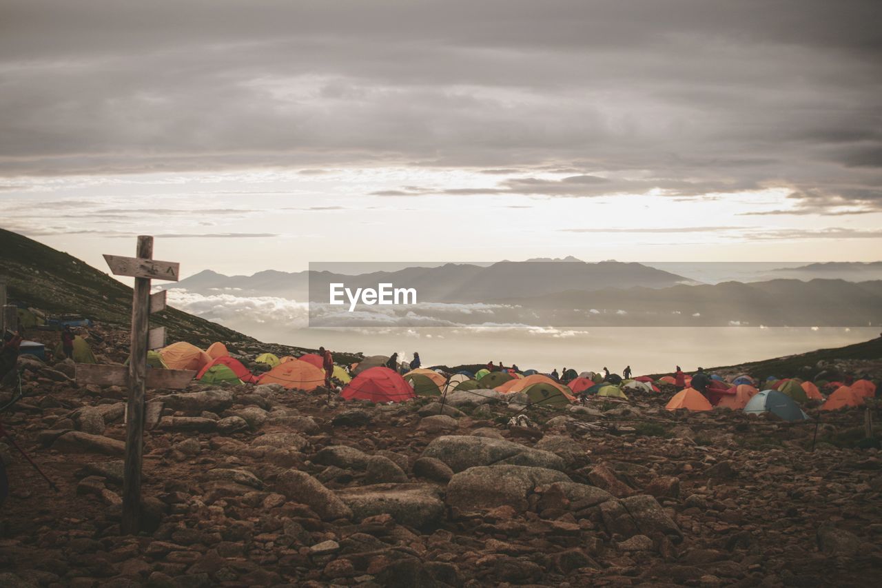 Tents on field against cloudy sky during sunset