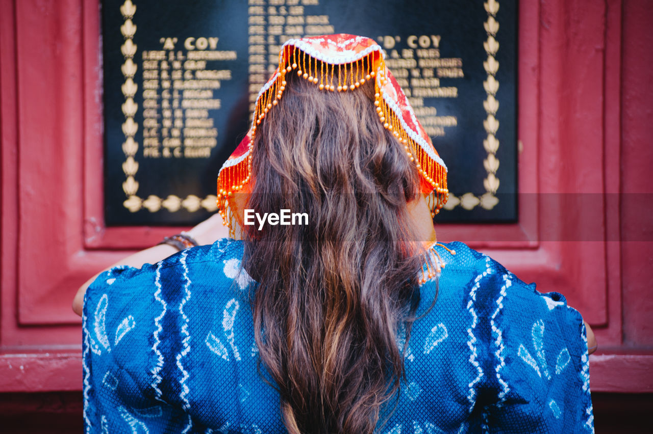 Rear view of young woman standing in front of blackboard