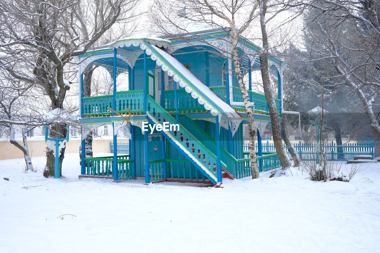 SNOW COVERED FIELD BY TREES AND BUILDING