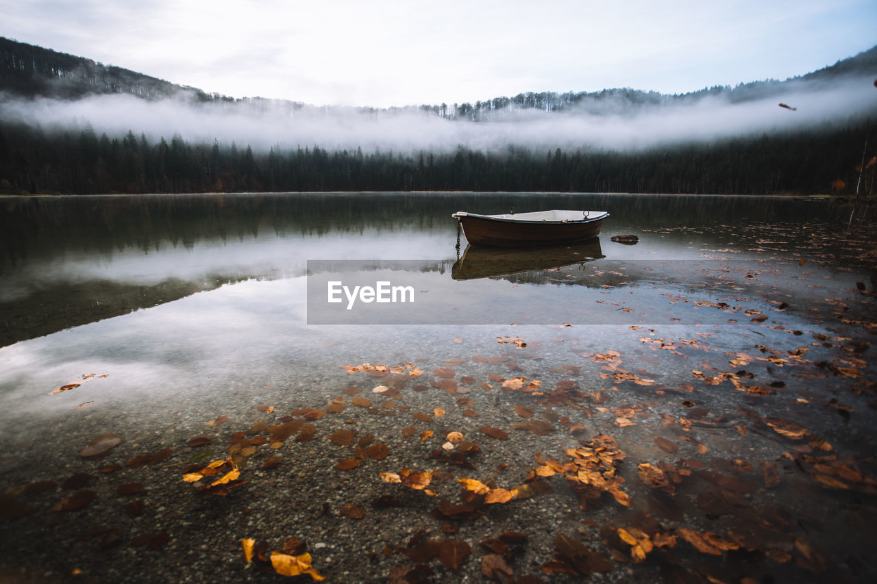 Boat moored in calm lake against trees