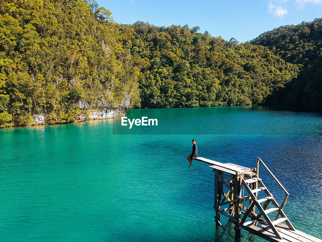 Man sitting over lake on diving platform