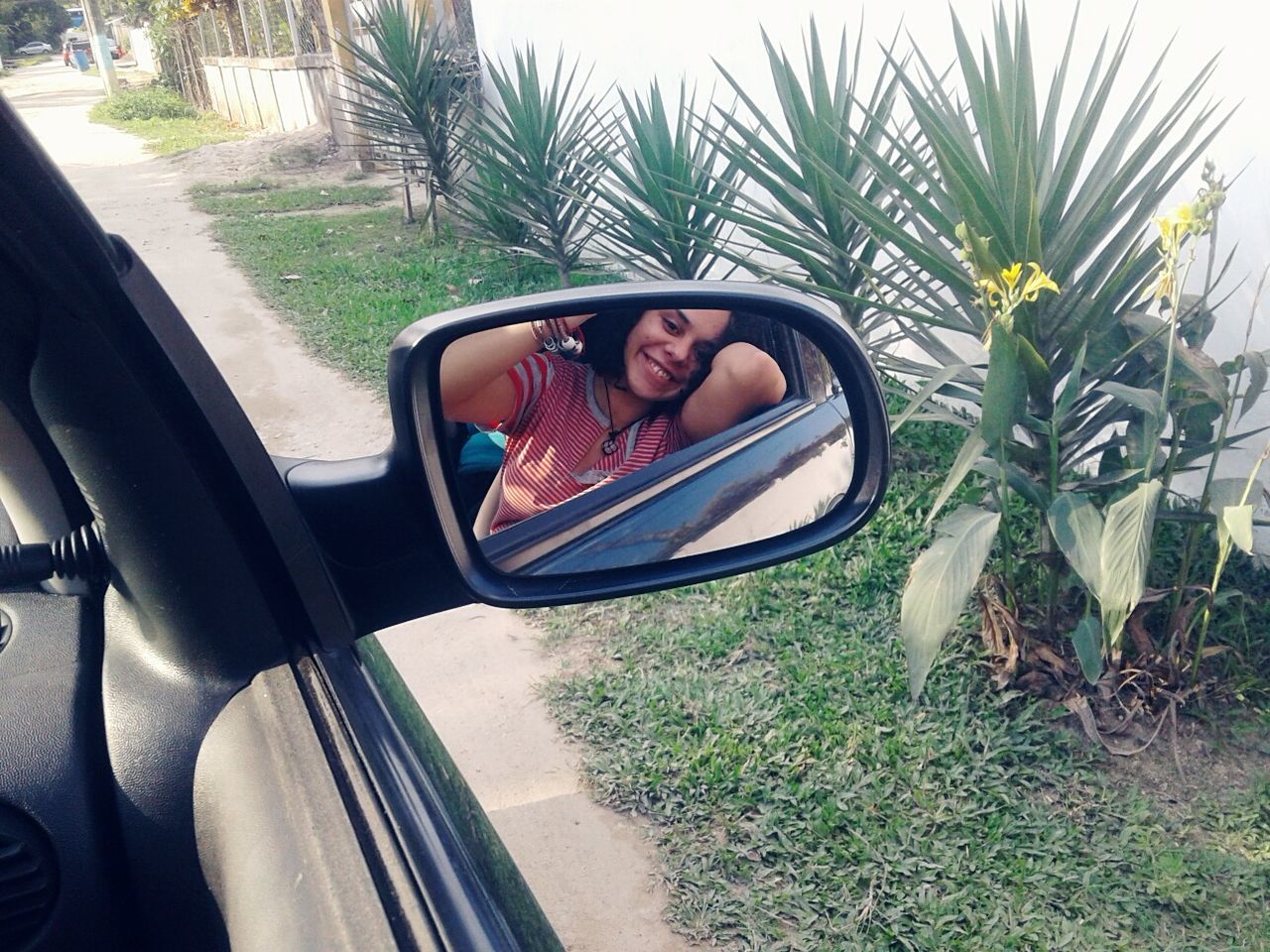 Reflection of woman on side-view mirror sitting in car