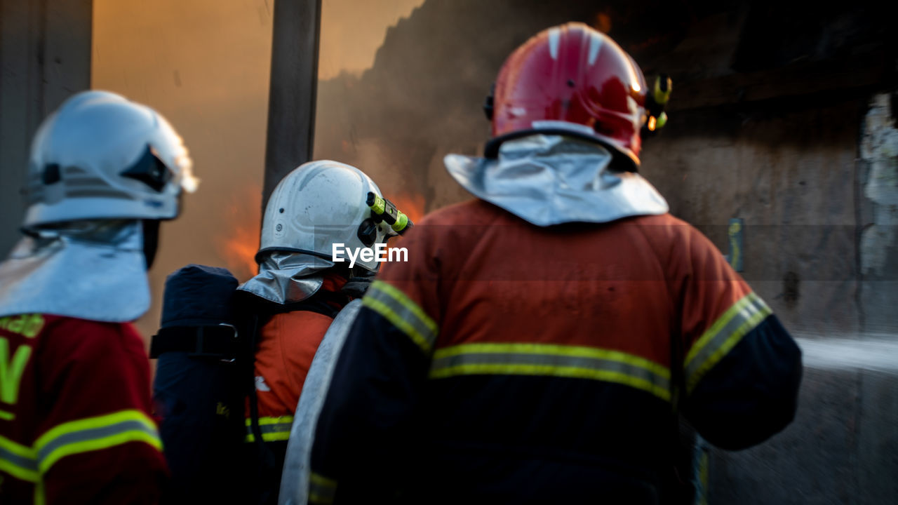 Rear view of firefighters working outdoors