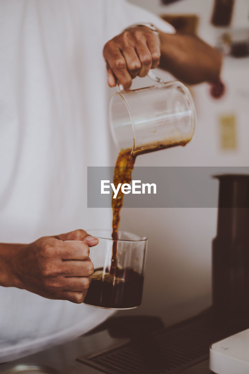 MIDSECTION OF MAN PREPARING DRINK IN GLASS