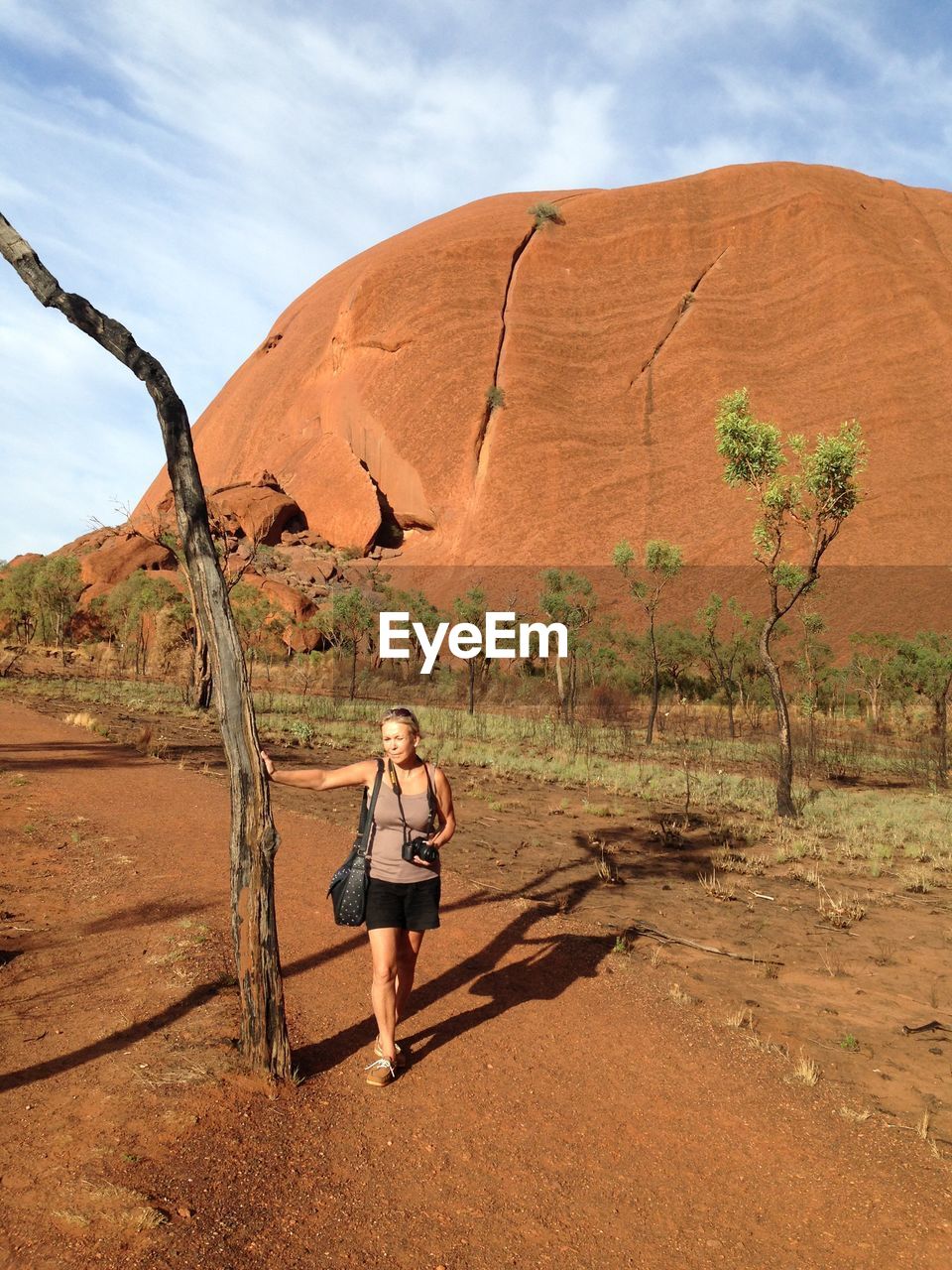 Full length of woman on landscape by tree trunk against sky