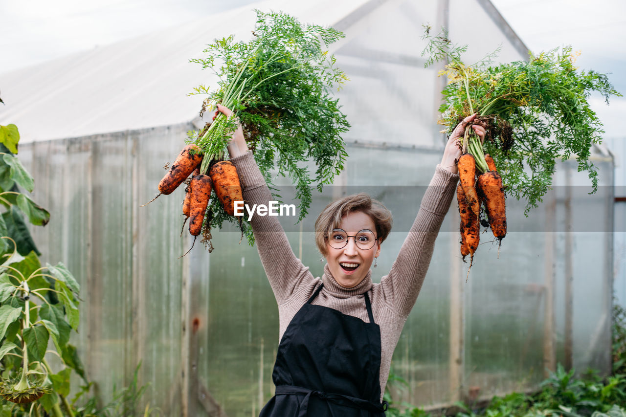 rear view of woman with arms outstretched standing against plants