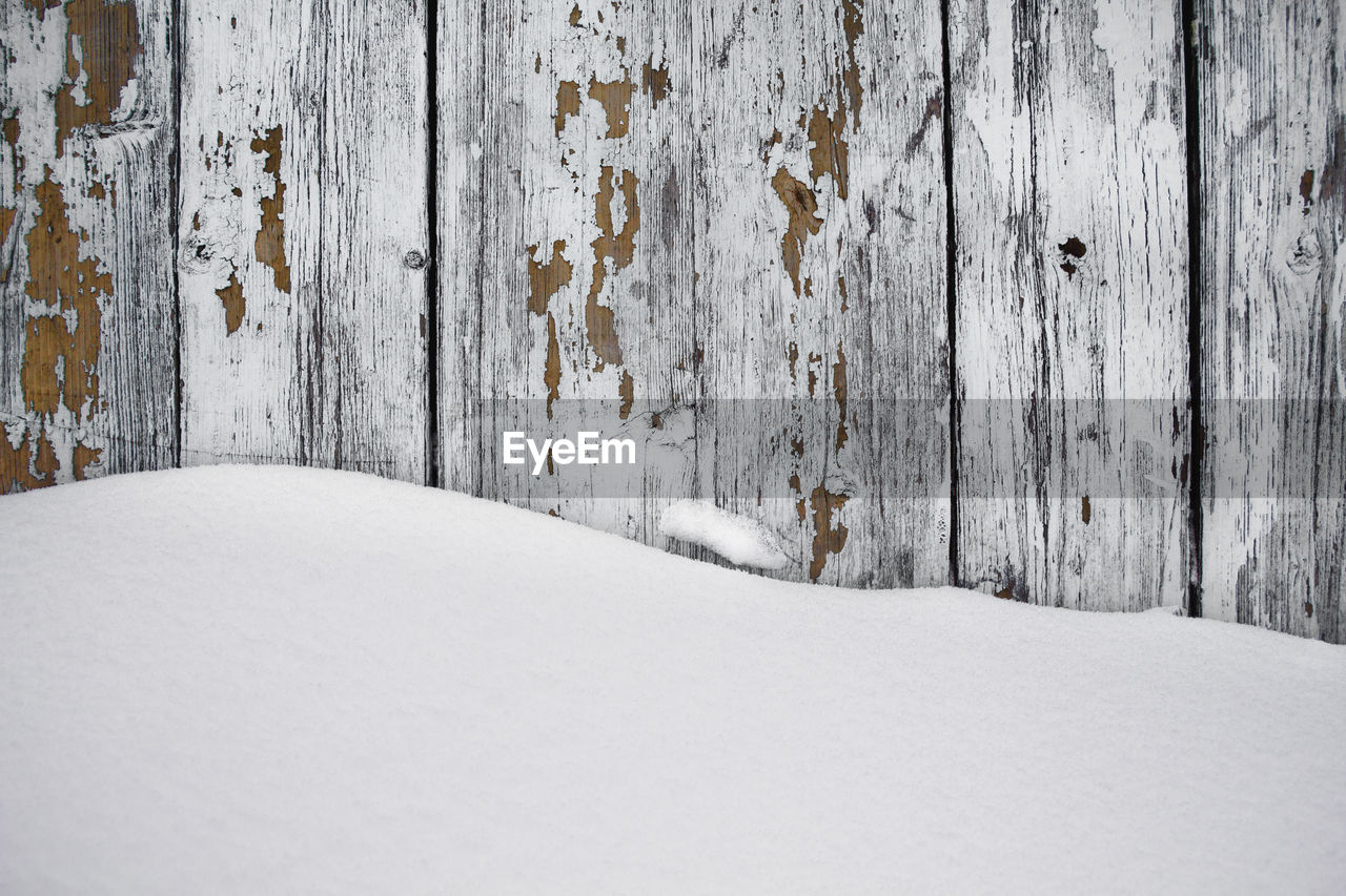 SNOW COVERED WALL BY WOOD