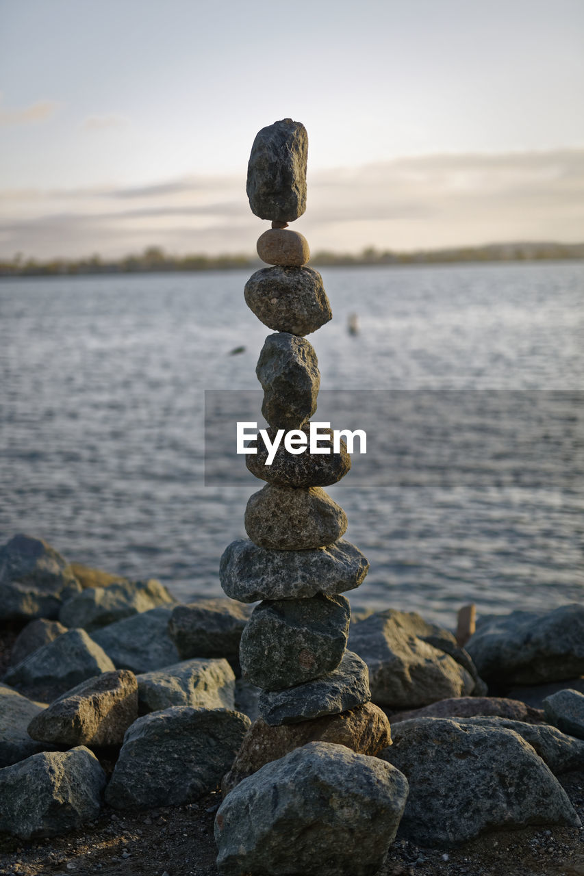 The art of rock balancing with water and sky in the background