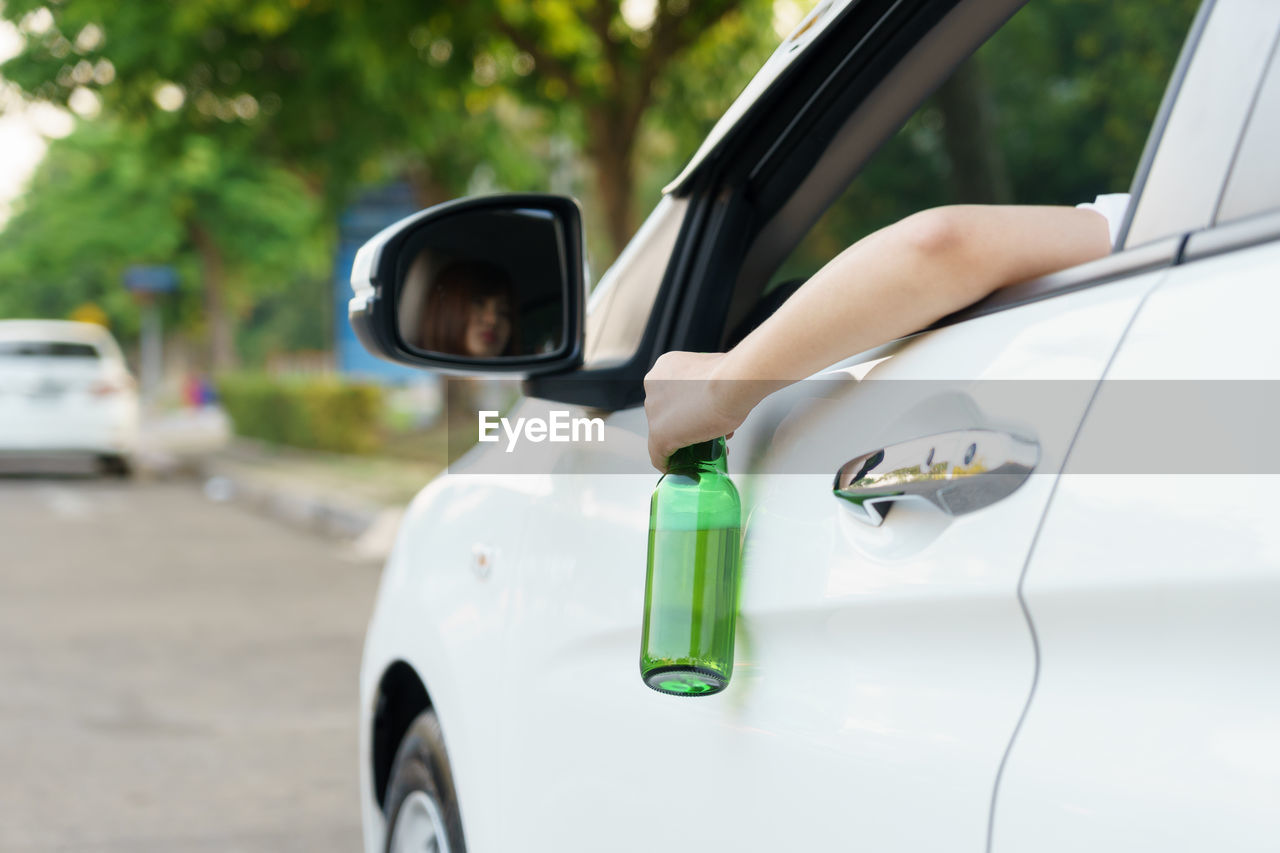 Woman holding beer bottle while driving car