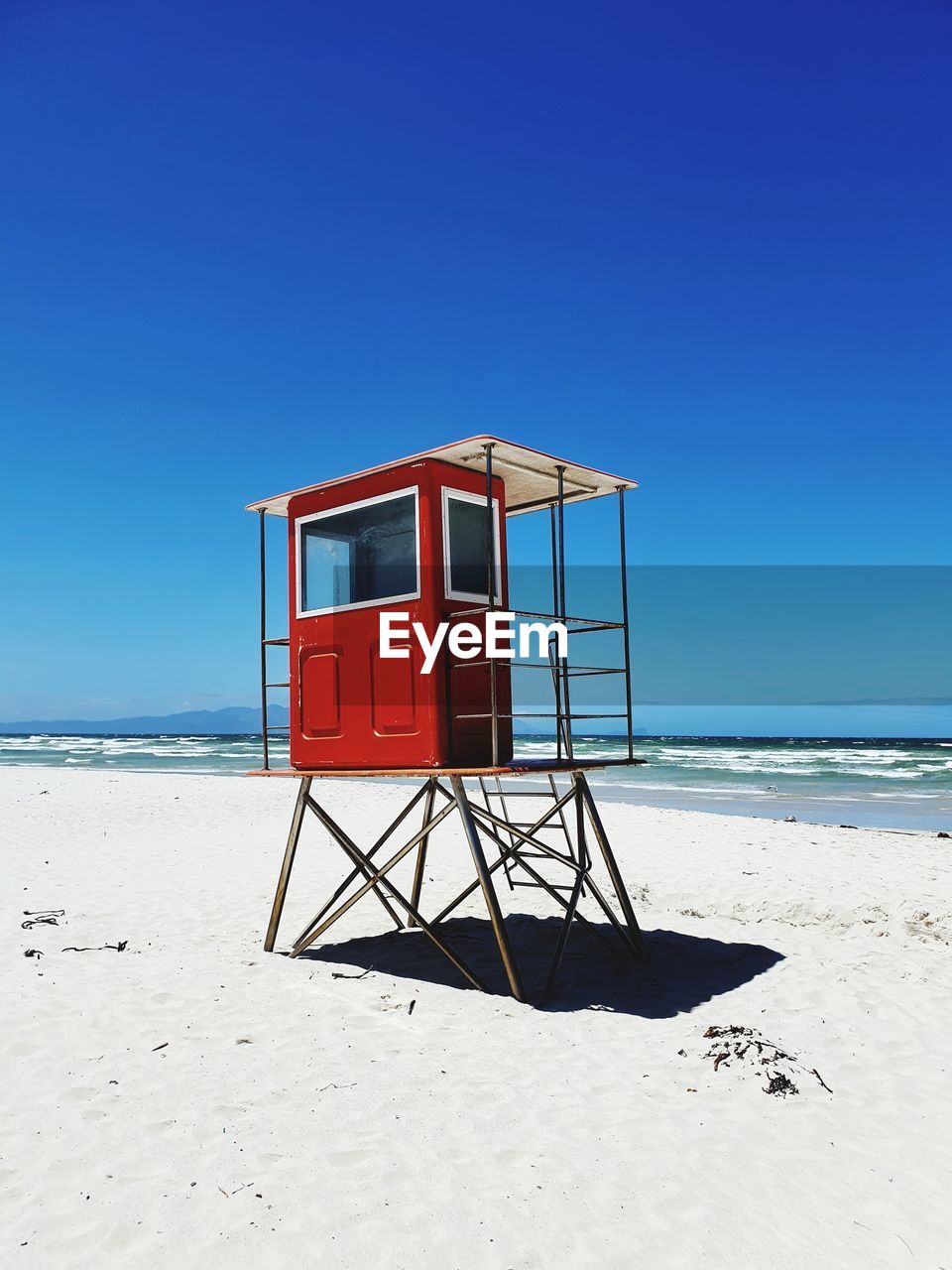 Lifeguard hut on beach against clear blue sky