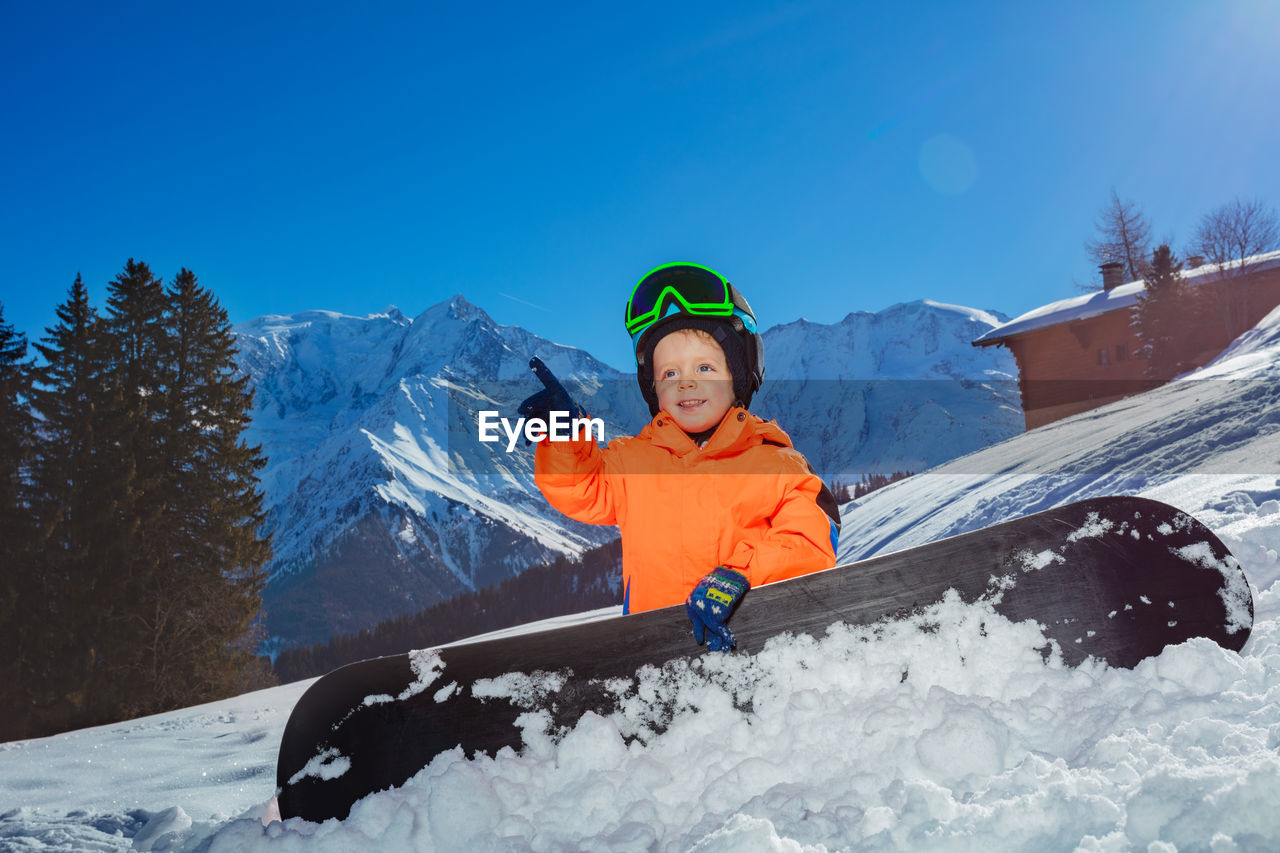 portrait of man skiing on snowcapped mountain against clear blue sky
