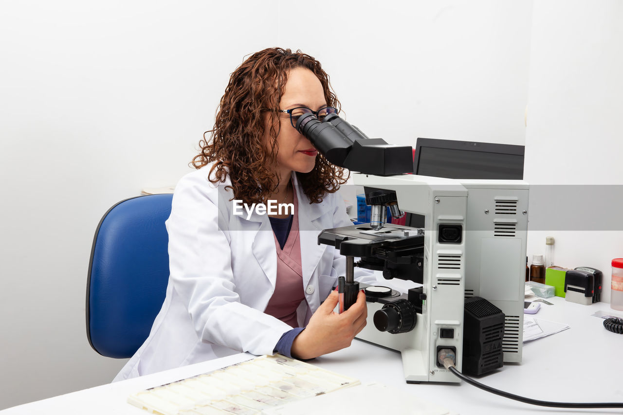 Cytologist looking at pap smear samples through a microscope. medical analysis concept.