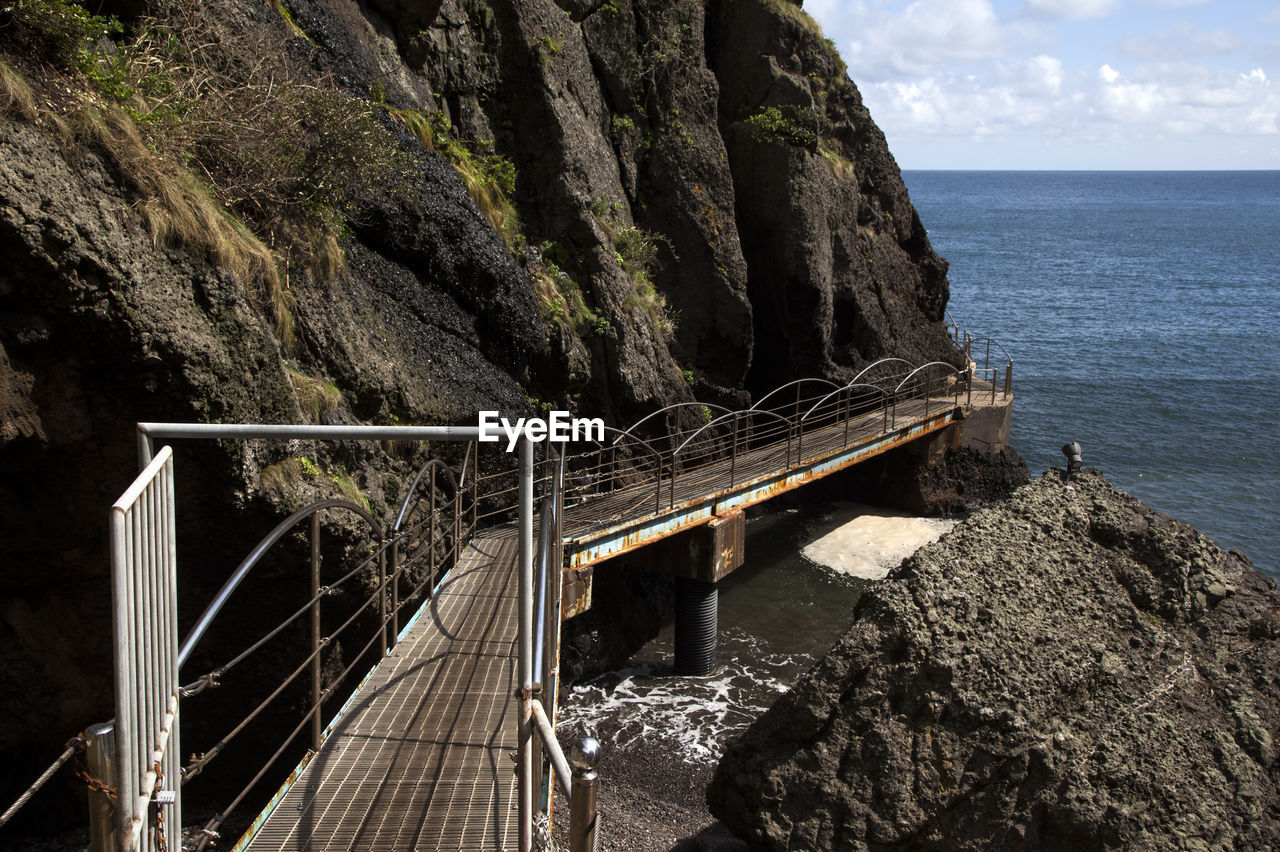 Bridge by rock formations against sea