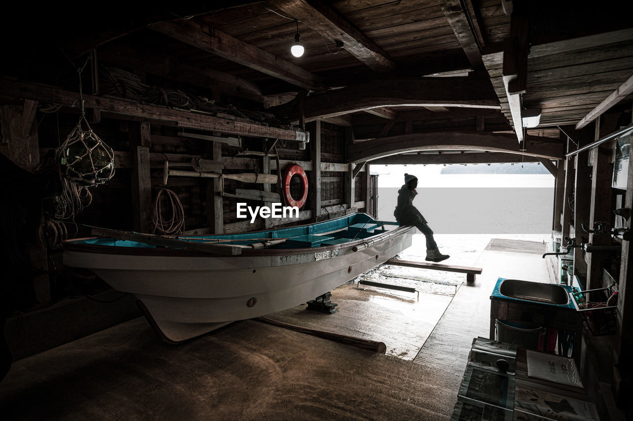 REAR VIEW OF MAN STANDING ON ABANDONED BOAT