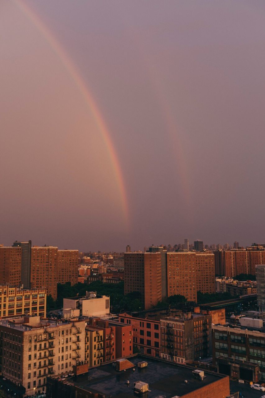 Rainbow over city against sky