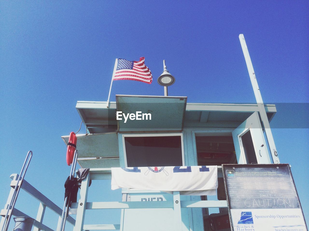 Low angle view of boat with american flag against clear blue sky