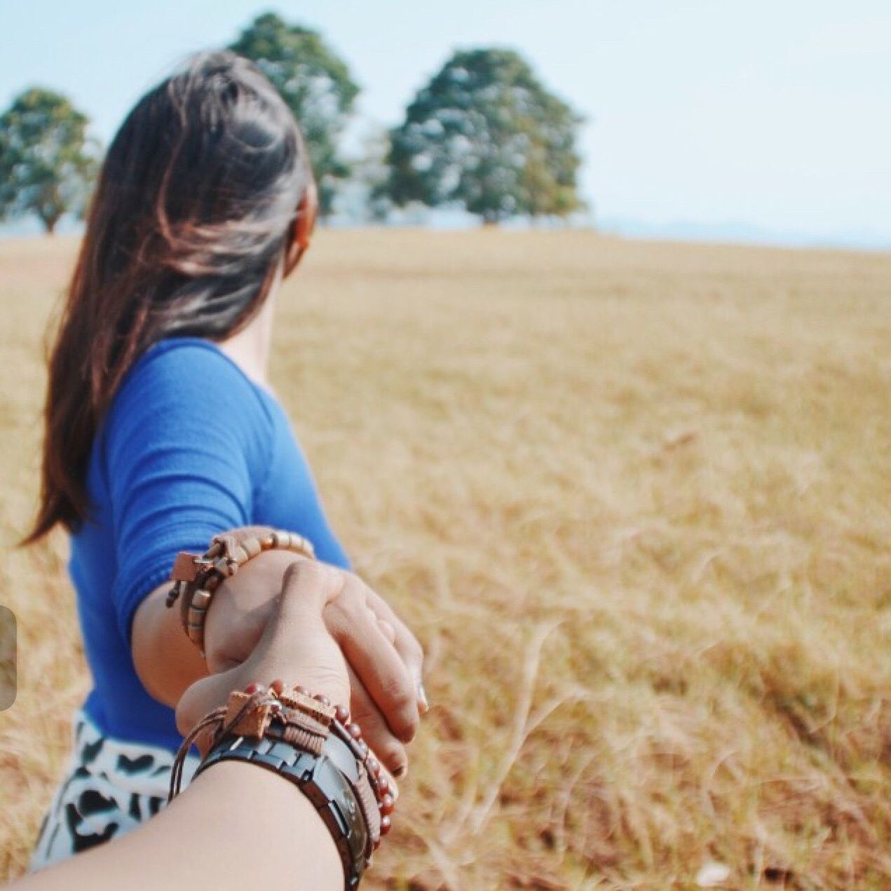 Close-up of man holding hands of woman on field