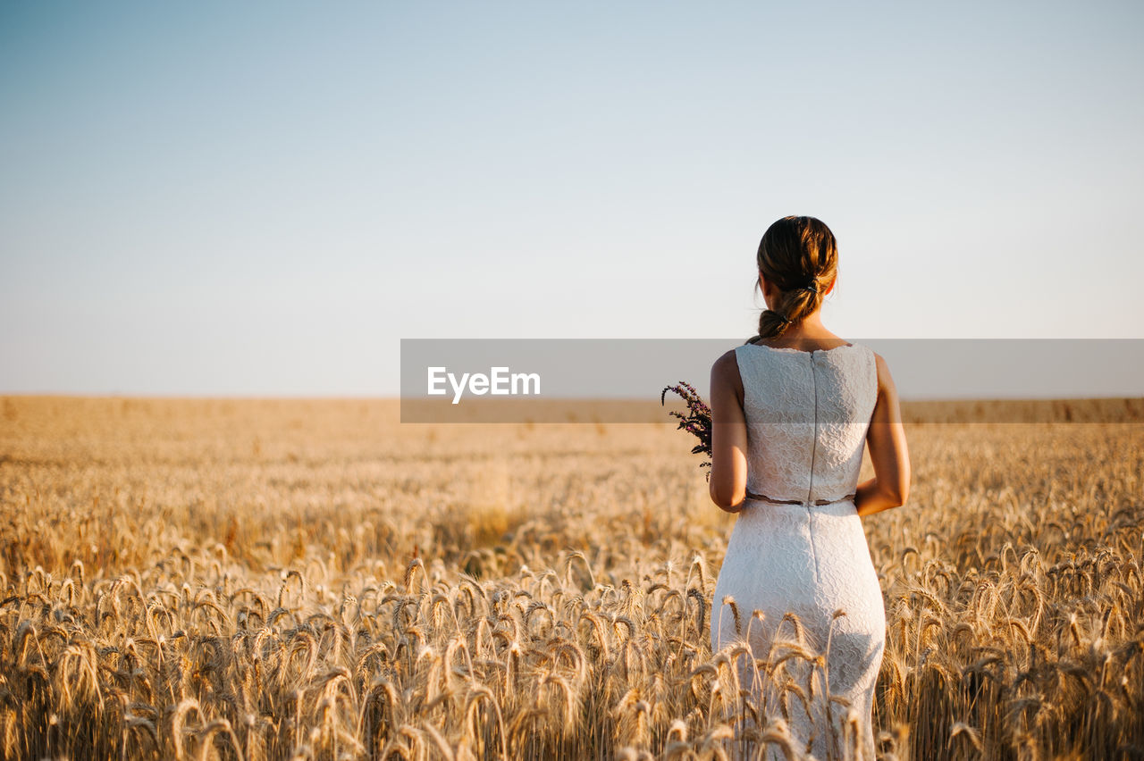 Woman standing on field against clear sky