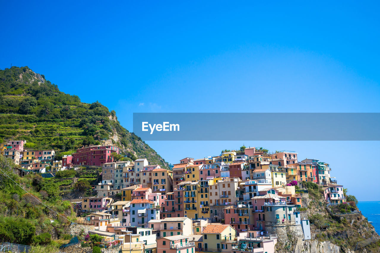 Buildings on mountains against clear blue sky