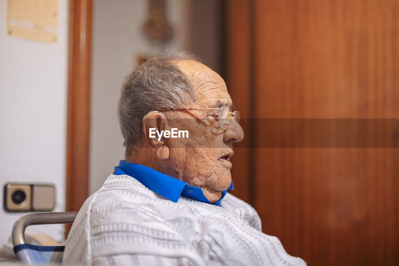 Close-up of senior man looking away while sitting at home