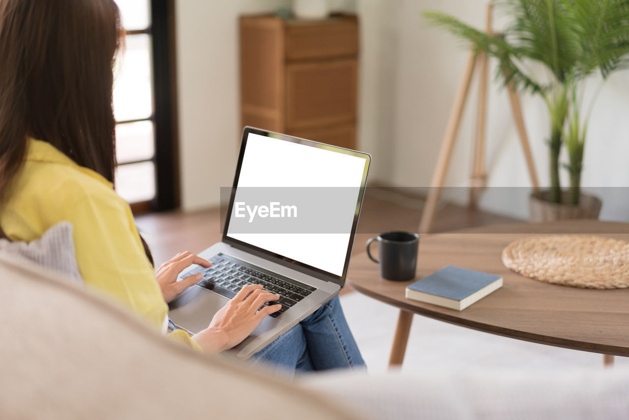 technology, computer, wireless technology, communication, adult, laptop, using laptop, one person, indoors, internet, women, furniture, computer network, business, table, working, writing, person, home interior, sitting, portability, using computer, casual clothing, domestic room, young adult, lifestyles, convenience, occupation, typing, clothing, business finance and industry, rear view, female, looking, domestic life, living room, computer equipment, office, desk, learning, relaxation, businesswoman, digital tablet, room, selective focus, hairstyle, e-mail, concentration, computer monitor, reading