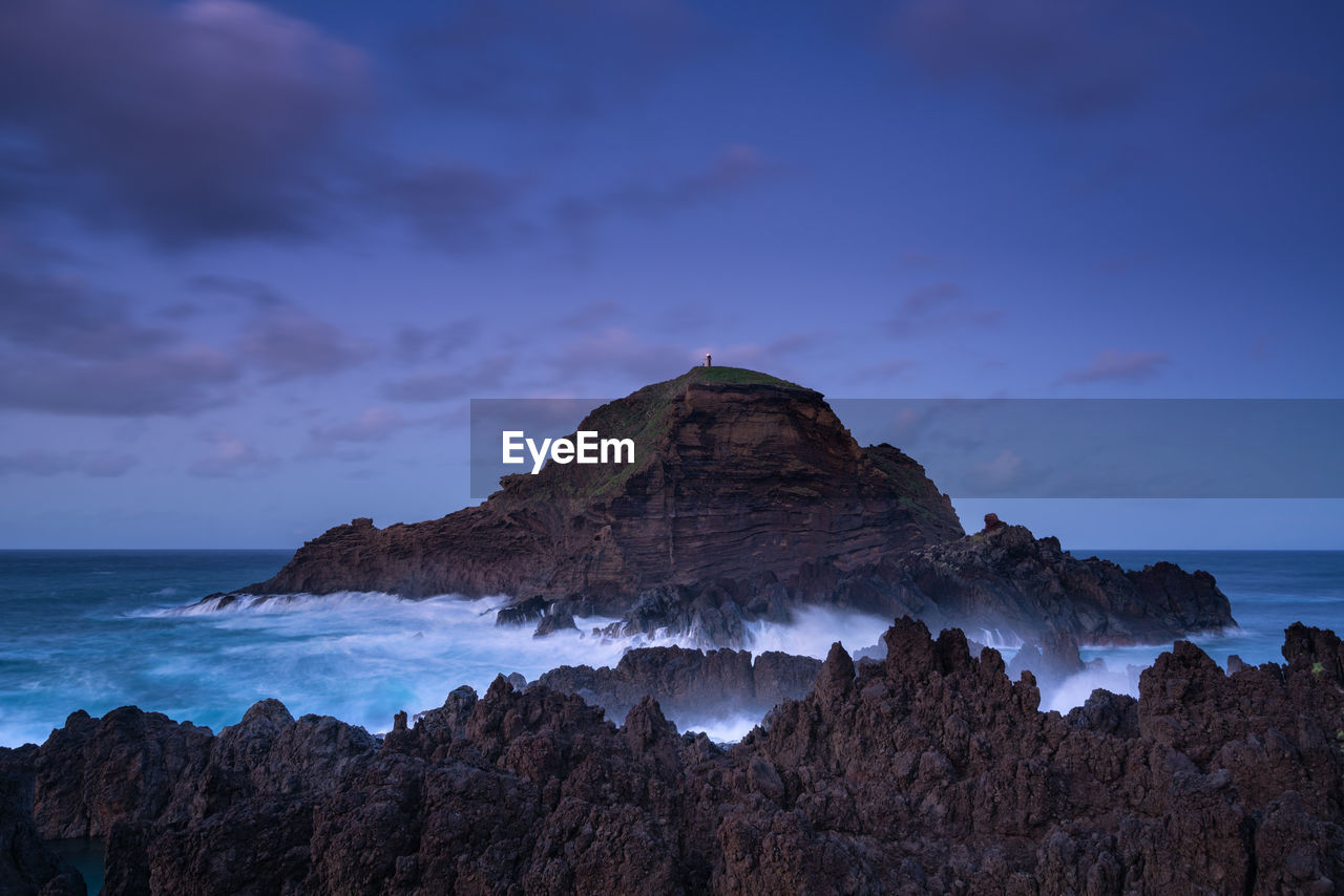 Rock formations on shore against sky