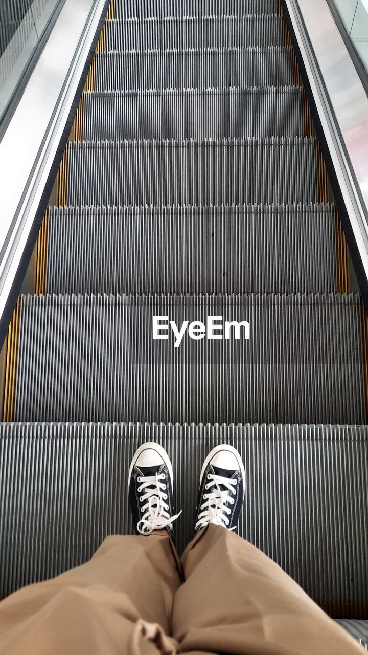 Low section of man standing on escalator