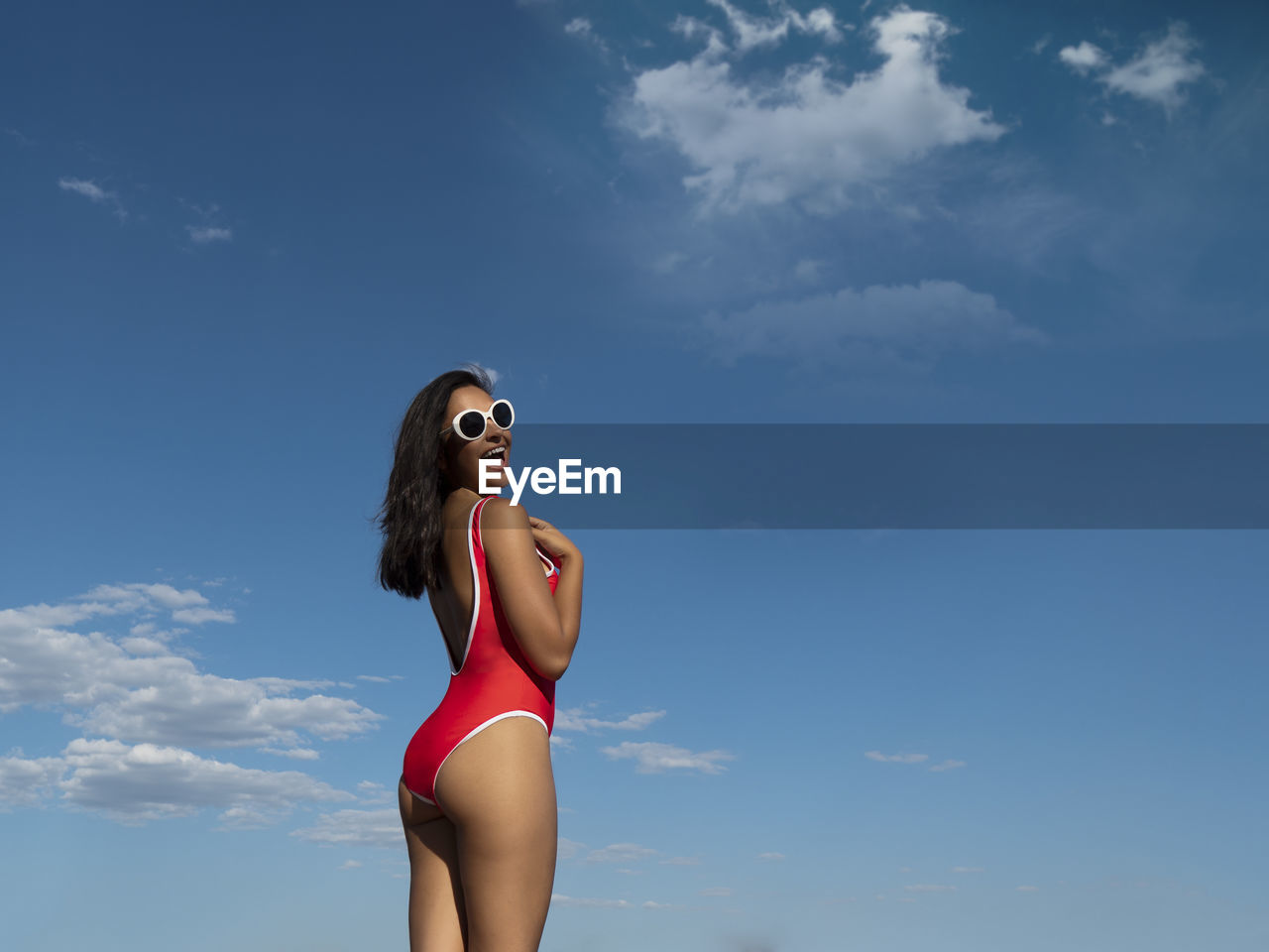 Portrait of young woman standing against sky