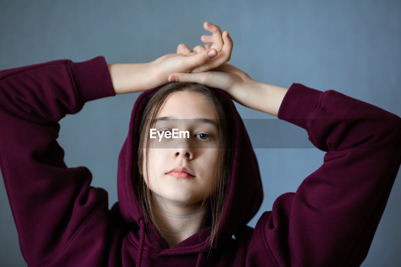 Portrait of teenage girl wearing hat against gray background