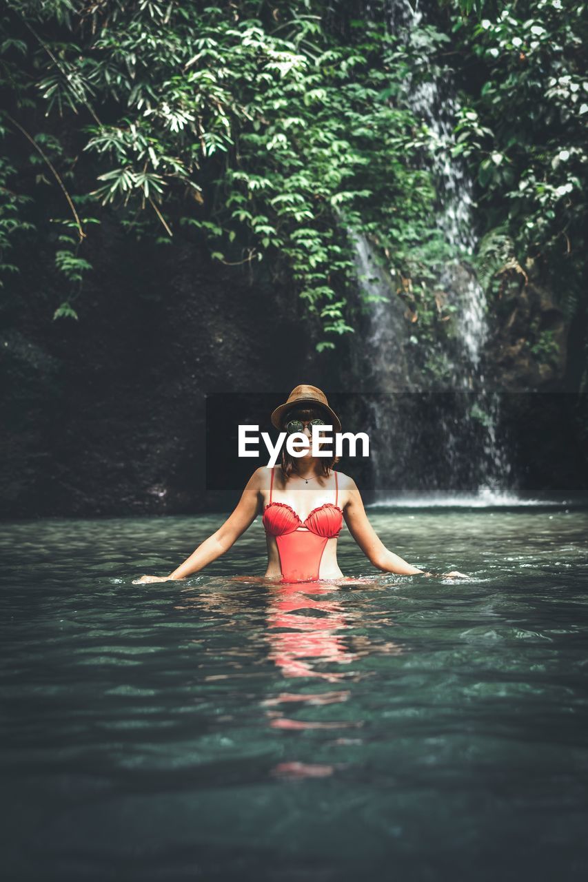 Portrait of woman standing in river at forest