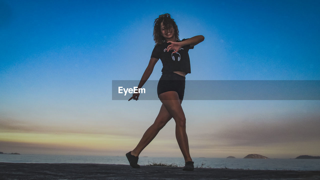 Full length of woman at beach against sky during sunset
