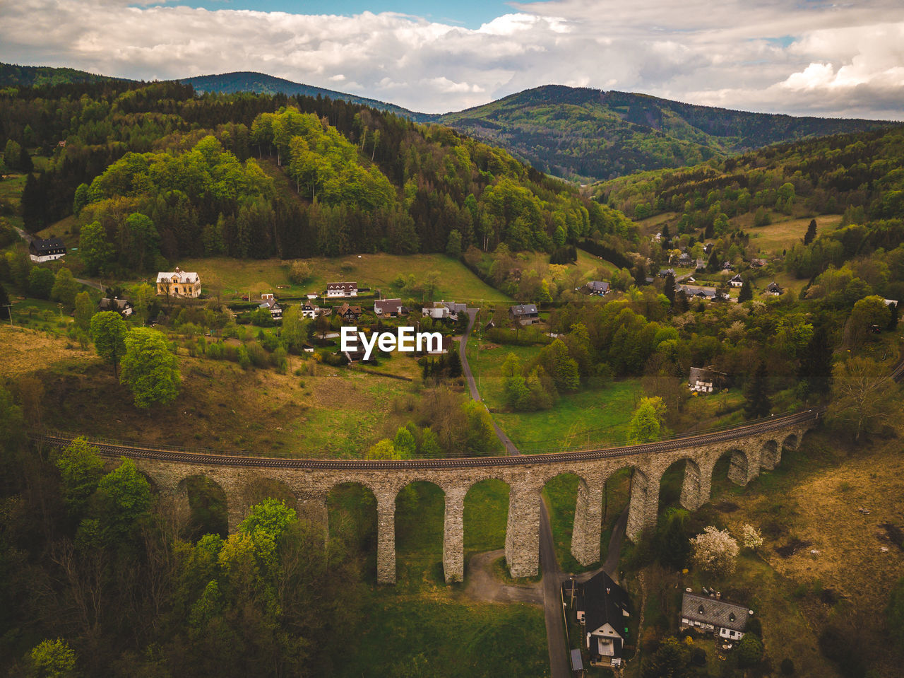 High angle view of rail arch bridge amidst buildings and mountains