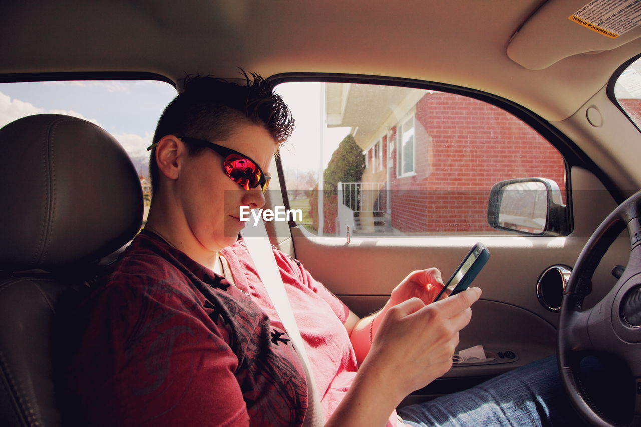 Young woman using mobile phone while sitting in car